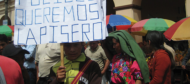 A young boy holds a sign that reads, "No queremos fuciles queremost lapisero."