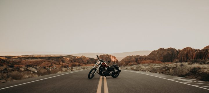 A motorcycle is parked in the middle of an empty desert road