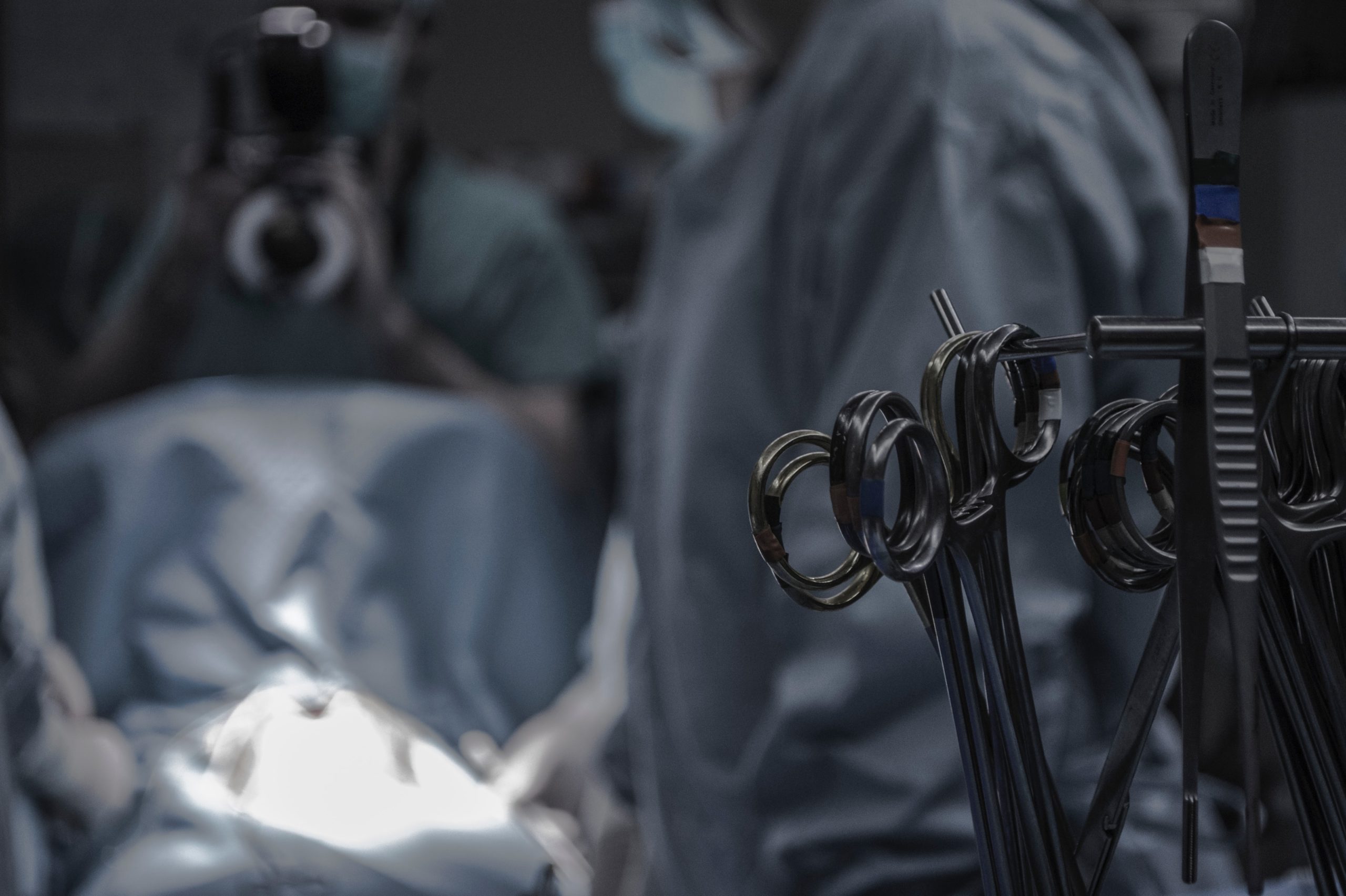 Photograph of an operating room with people and surgical implements visible.
