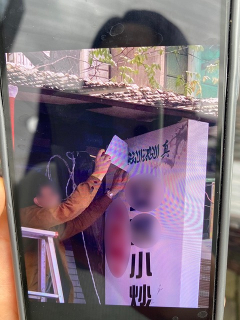 Photograph of someone covering up a portion of a sign